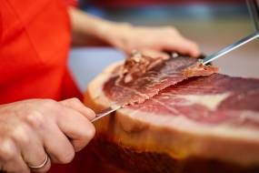 professional-cutter-carving-slices-from-whole-bone-serrano-ham-min_original